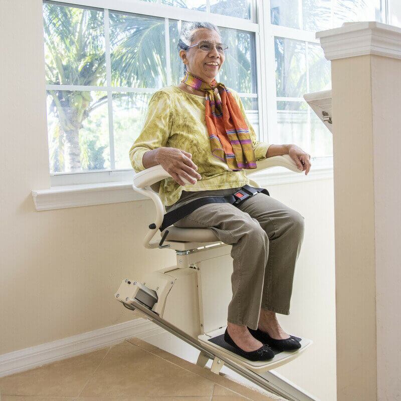 Harmar-209-SL300-L-BAP-112021_scr Woman on Harmar stairlift at top of stairs