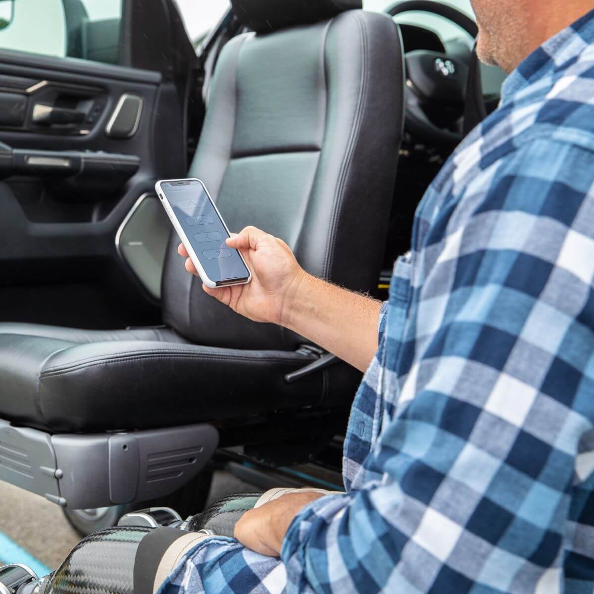 Turny_2019_Truck_015_High A person in a plaid shirt uses a smartphone while sitting next to an open car door with a swivel seat.