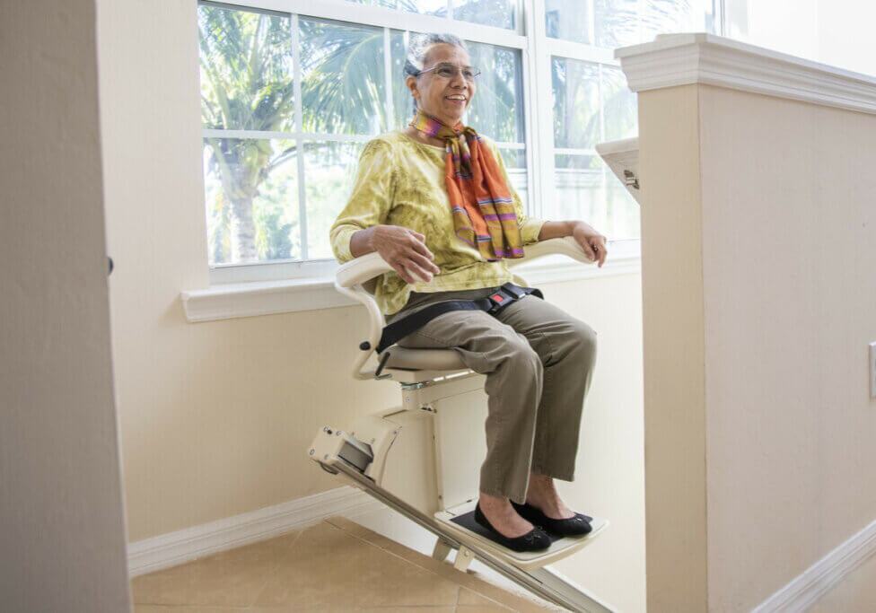 Woman on Harmar stairlift at top of stairs