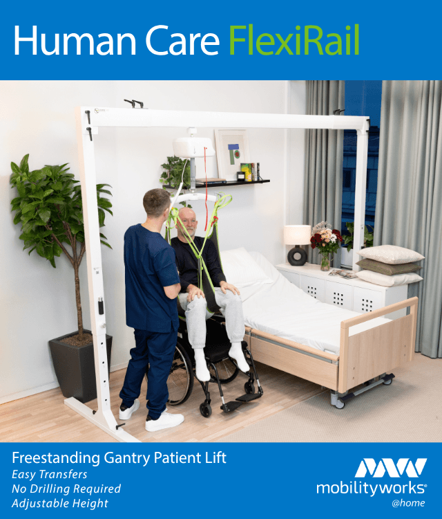 A nurse assists an elderly man in a wheelchair using a gantry patient lift next to a hospital bed in a modern, well-lit room.