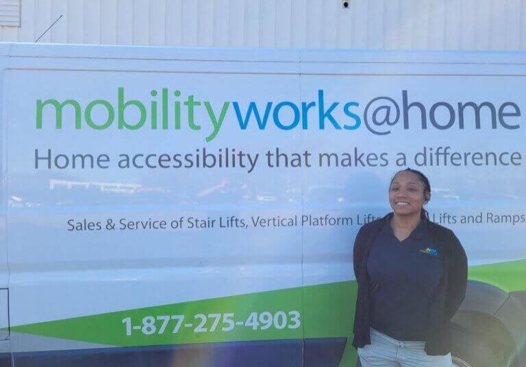 A person stands in front of a van labeled mobilityworks@home, offering home accessibility solutions and services, including stairlift installations.