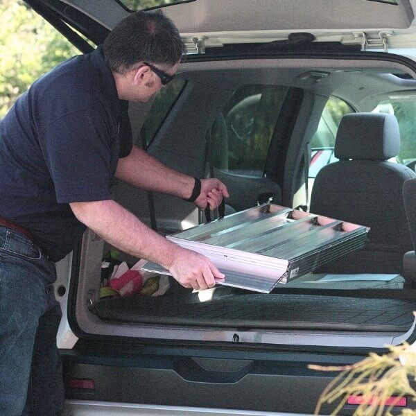 Man putting folding wheelchair ramp into vehicle