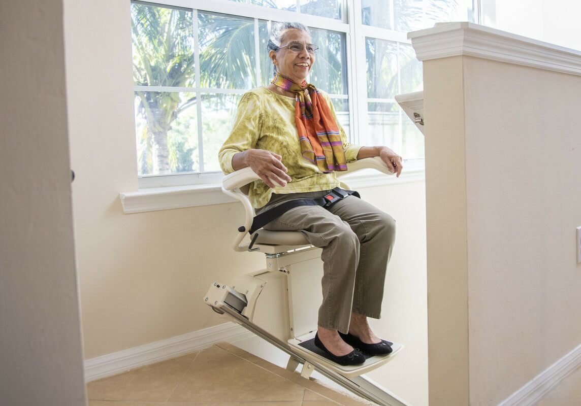 Harmar-209-SL300-L-BAP-112021_scr Woman on Harmar stairlift at top of stairs